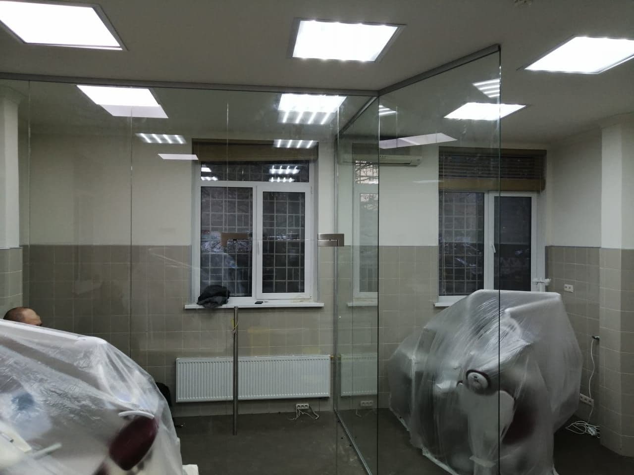 Перегородки от производителя в стоматологии: стекло без стоек делит кабинеты, кресла ещё под плёнкой