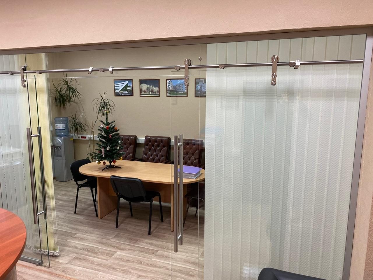 Цельностеклянная раздвижная перегородка переговорной: полотно с матовыми полосами сдвигается по штанге на роликах