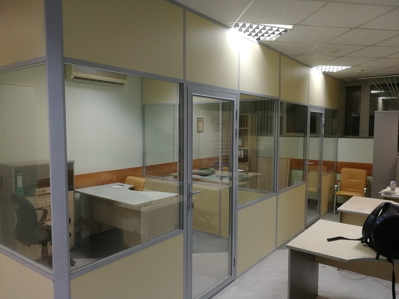 Комбинированные офисные перегородки: бежевые глухие панели, посередине стекло с жалюзи, за ним рабочие столы