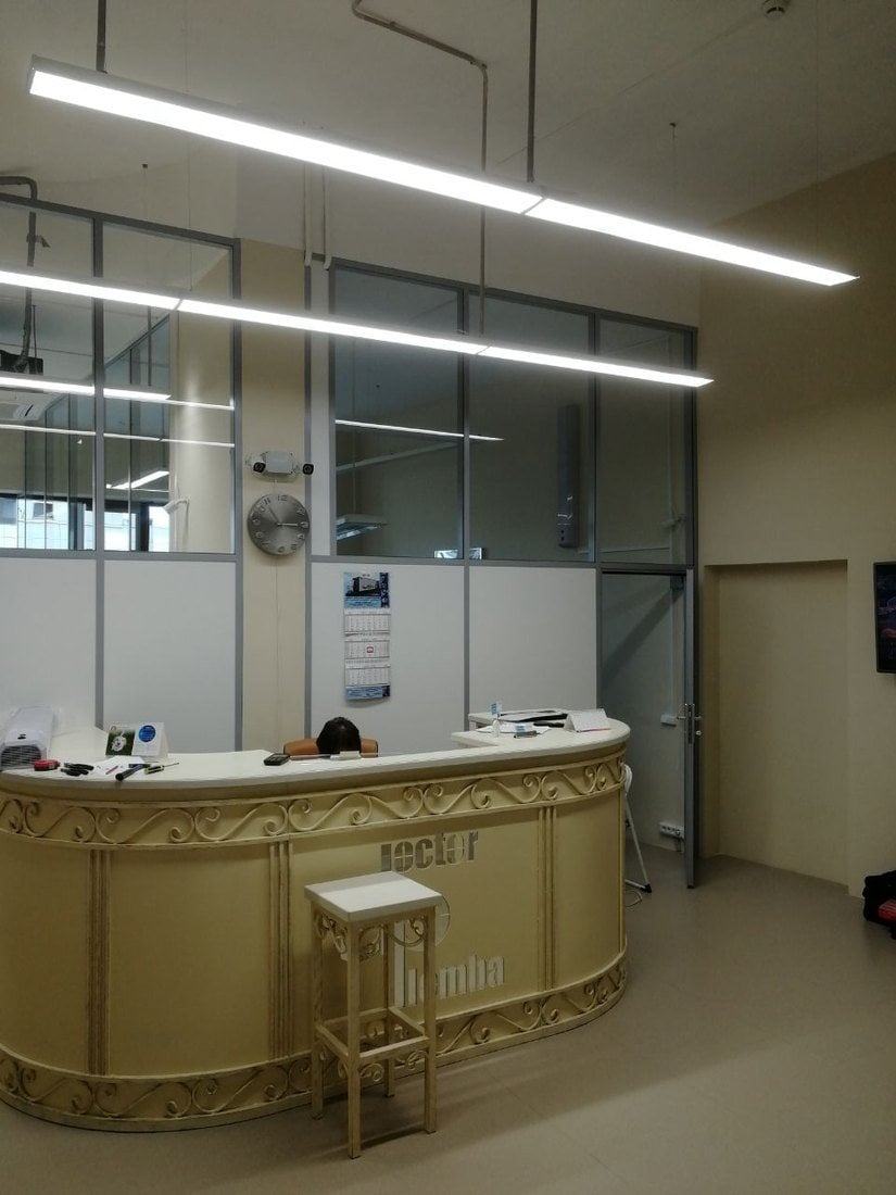 Стойка регистратуры клиники, за ней перегородка с глухим низом и остеклением до потолка