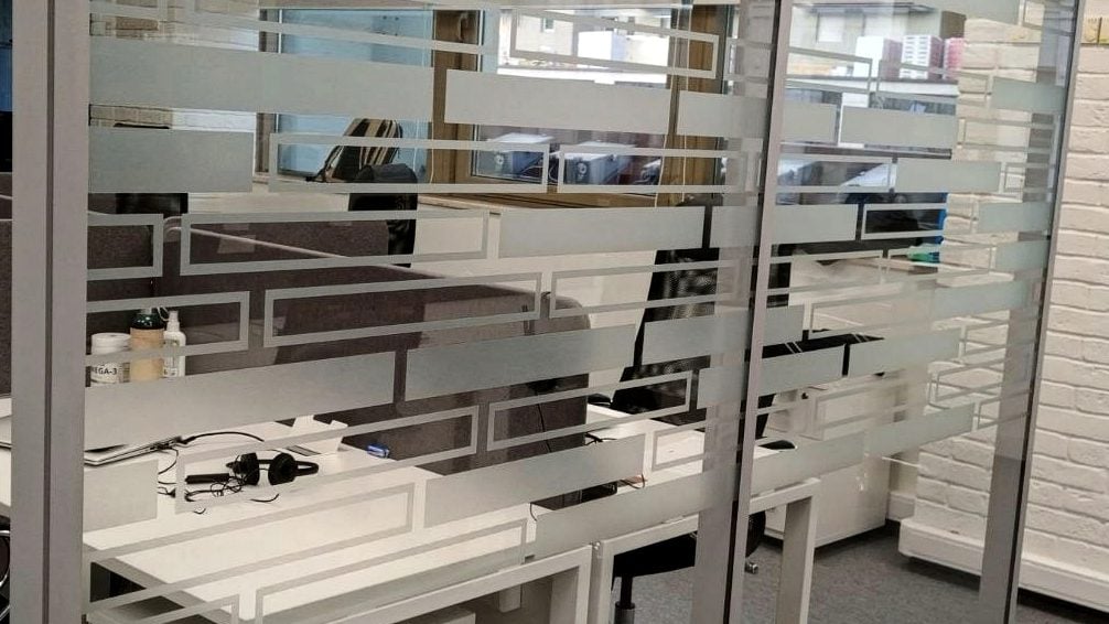 Узор из полос и прямоугольников вырезан плоттером Геометрический узор из плёнки на остеклении рабочей зоны: полосы и прямоугольные контуры в один ряд