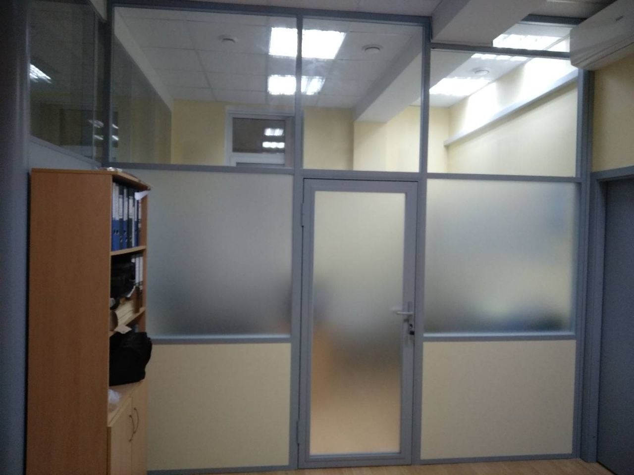 Серый профиль и дверь с матовой вставкой: рабочая комната отделена от прохода Три пояса заполнения в перегородках для офиса: панель снизу, матовый посередине, прозрачный под потолком; серый профиль и дверь