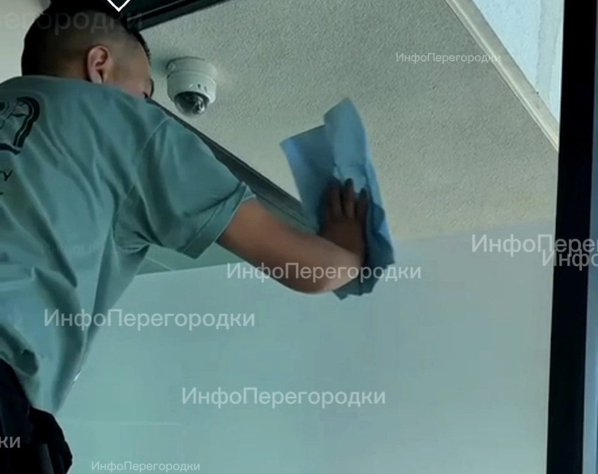 Синяя салфетка в руке мастера, остекление до потолка Мастер протирает стекло салфеткой: остекление в тёмном профиле
