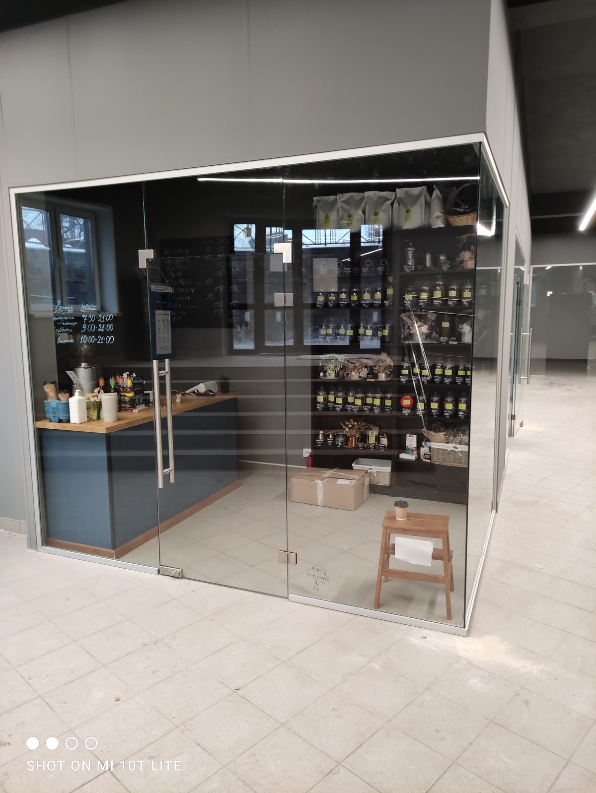 Цельностеклянная перегородка в торговом центре — бутик с маятниковой дверью и зажимным профилем