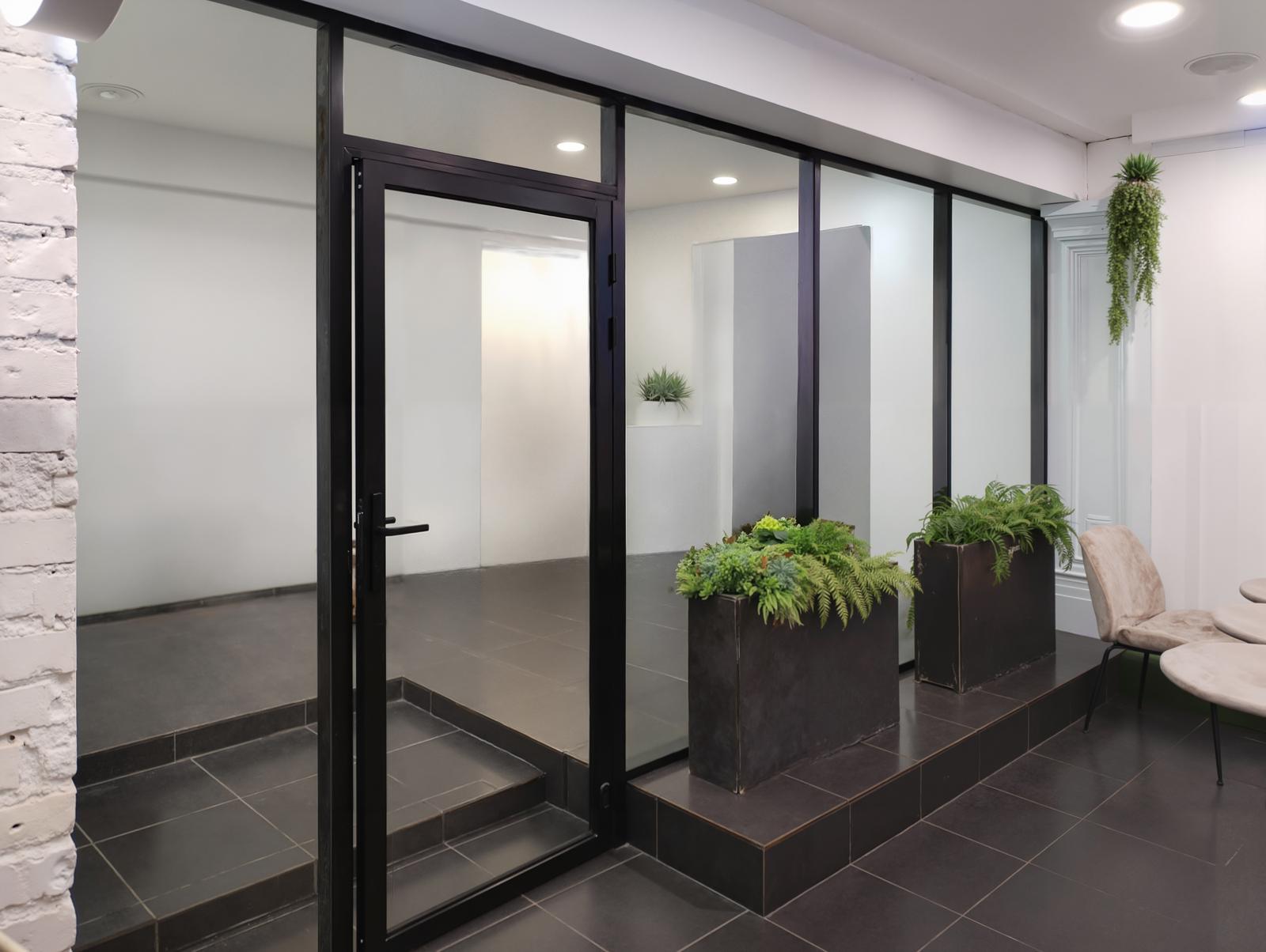 Распашная стеклянная дверь в офисной перегородке из тёмного алюминиевого профиля