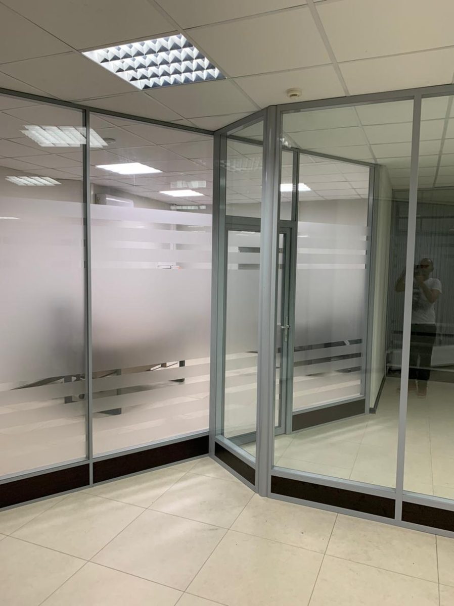 Стеклянная перегородка с матовыми полосами в офисе