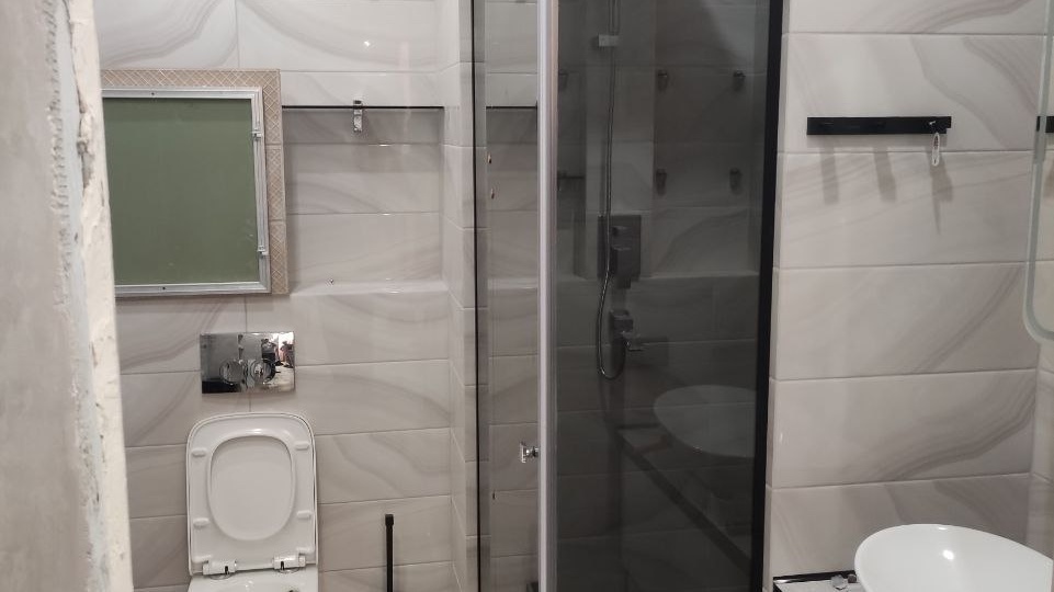 Стеклянная перегородка с чёрным каркасом и распашной дверью — пример душевого ограждения